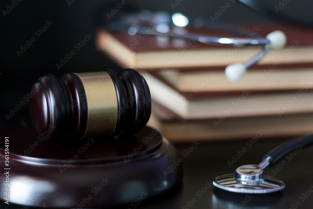 Judge's gavel and stethoscope with law books on the background Judge's gavel and stethoscope with law books on the background