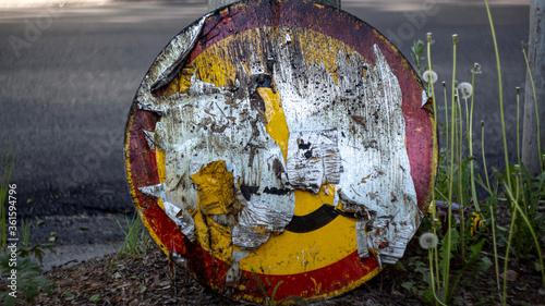 A broken and forgotten road sign lies in the grass. disregard for traffic rules.