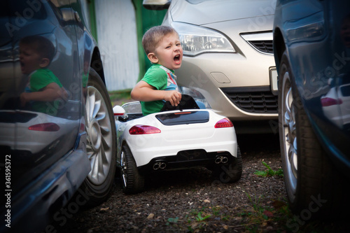 Cute boy in riding a white electric car. Funny boy rides on a toy electric car.
