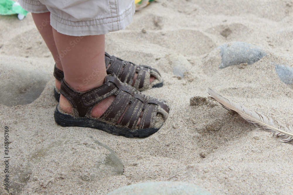 feet in sandals on the sand