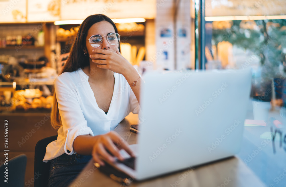 Thoughtful woman browsing laptop in cafe