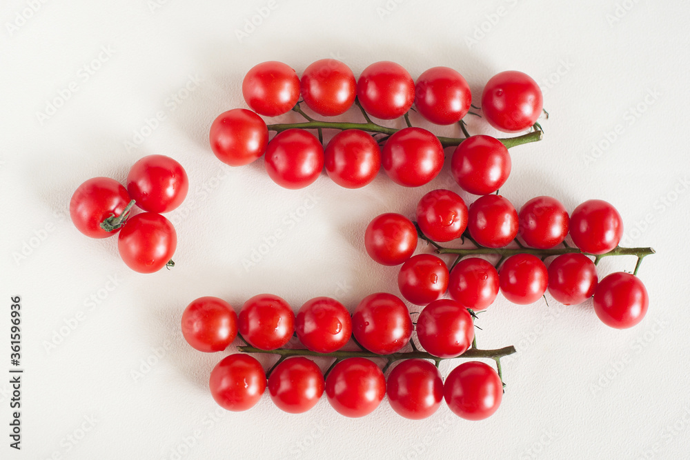 Three sprigs of cherry tomatoes on a light background. The view from the top Three sprigs of cherry tomatoes on a light background. The view from the top
