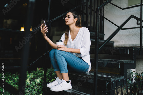Modern young woman using smartphone on stairs