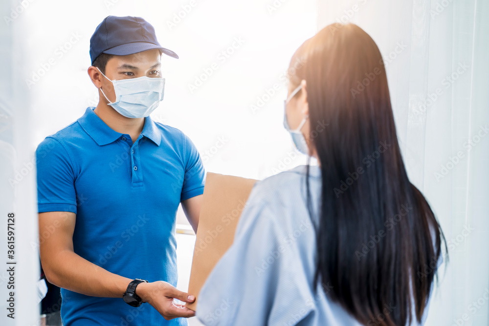 Deliveryman delivering package box parcel giving to female customer at home wearing face mask safety coronavirus covid-19 infection customer delivery service logistics ordering mail posting business