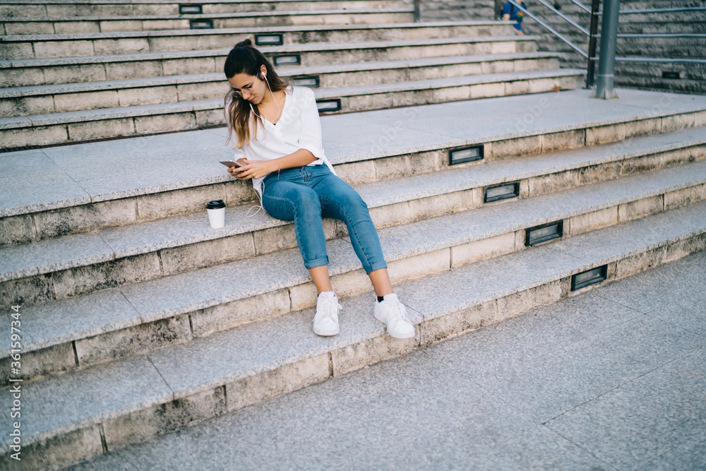 Young woman watching smartphone on stairs
