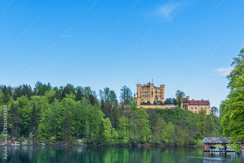 Fototapeta premium View of the Hohenschwangau Castle. Panorama of a lake with a castle and a pier. Germany, Bavaria, Schwangau.