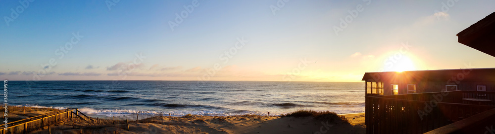 Beautiful beach with red yellow sand, deep blue ocean water and blue sky with clouds in sunny new sunrise day. Panoramic view. Natural background for peaceful summer vacation.
