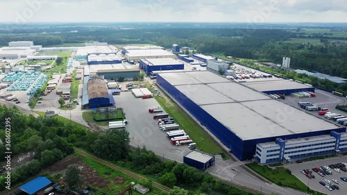 Aerial circling view of logistics center with warehouse, loading hub with many semi-trailers truck load.