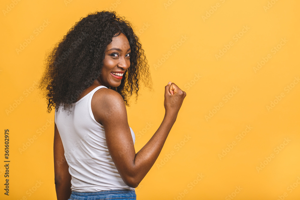Happy winner! Young African American black woman isolated on yellow background giving a thumbs up gesture.