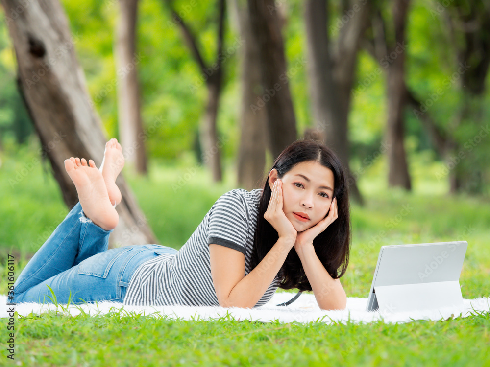 A beautiful Asian woman is relaxing in the garden, Read and search for learning information from the internet A beautiful Asian woman is relaxing in the garden, Read and search for learning information from the internet