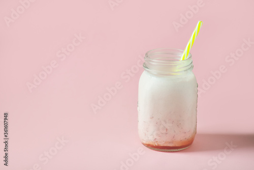 milk strawberry smoothie in jar with yellow straws on pink background