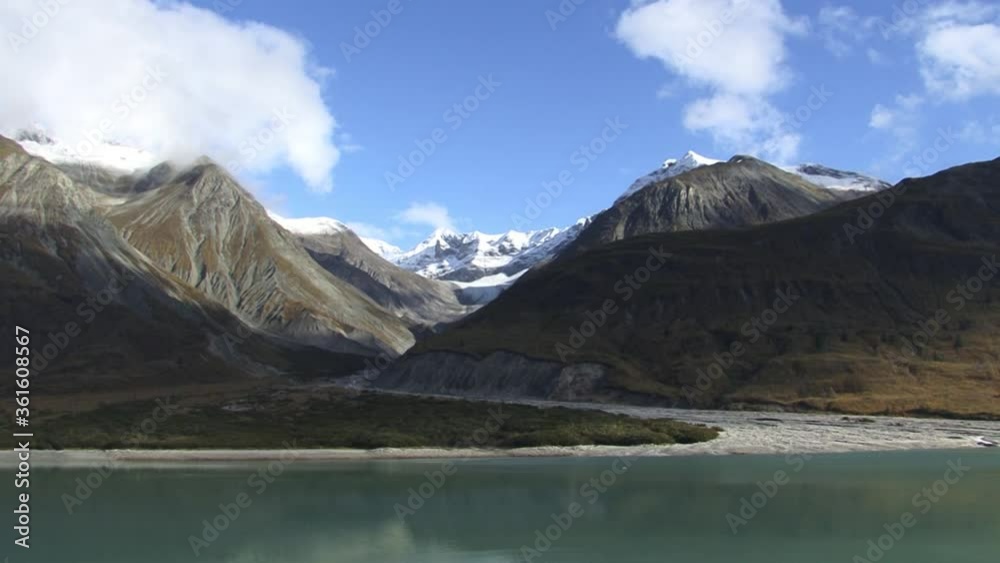 Glacier bay Alaska mountains in a sunny day with blue sky and puffy white clouds. Beautiful landscape shot of mountains and the bay waters. Glacier bay Alaska mountains in a sunny day with blue sky and puffy white clouds. Beautiful landscape shot of mountains and the bay waters.