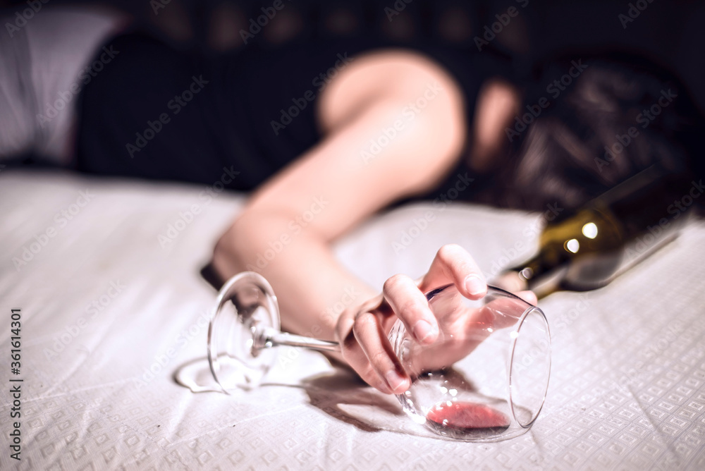 Φωτογραφία a young girl suffering from chronic alcoholism lies in a dirty room, next to a bottle of wine and a glass