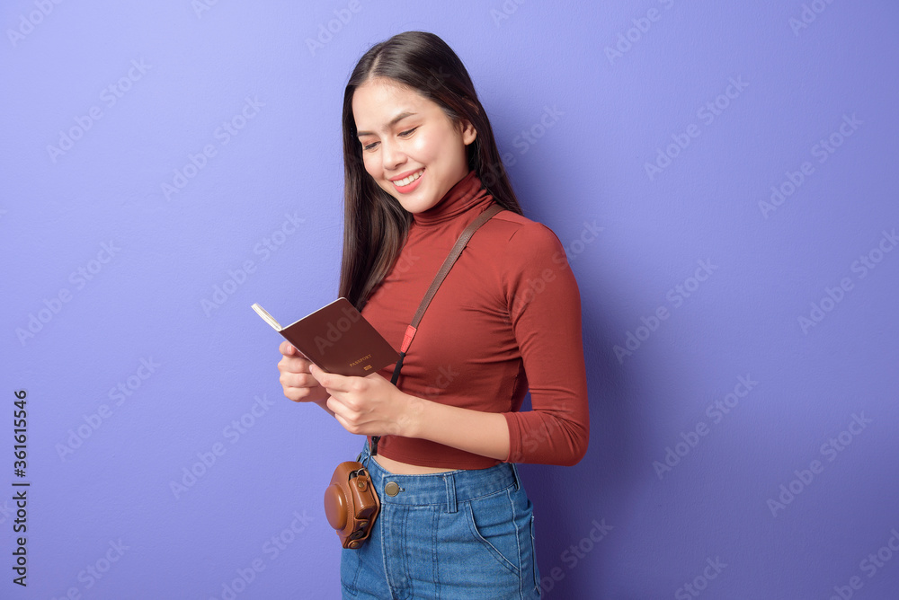 portrait of young happy beautiful woman is traveling aboard with passport over isolated purple background studio portrait of young happy beautiful woman is traveling aboard with passport over isolated purple background studio