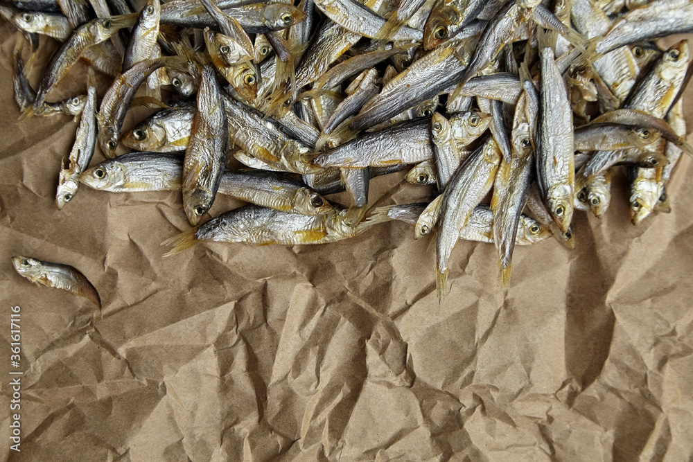 Dried salted fish on crumpled parchment paper background. Dried salted fish on crumpled parchment paper background.