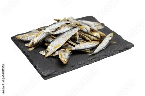 Small dried fish on slate board isolated on white background