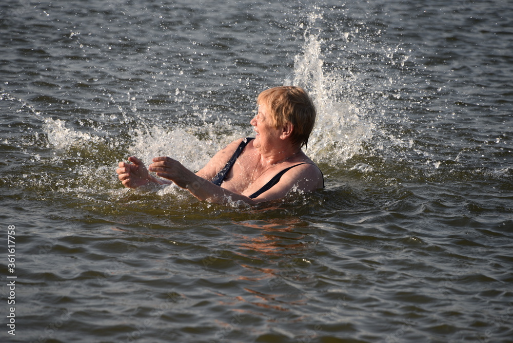 grandson in the lake sprinkles fun on grandmother with water
grandson in the lake sprinkles fun on grandmother with water