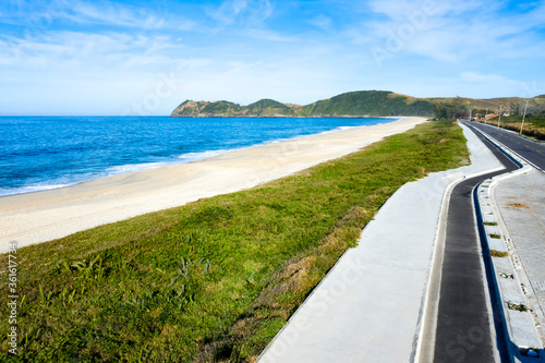 I walk by the sea. Beautiful beach and a road. Long Road to the middle of nowhere. The landscape has taken at Jacone Beach, Rio de Janeiro state, Brazil, South America. 