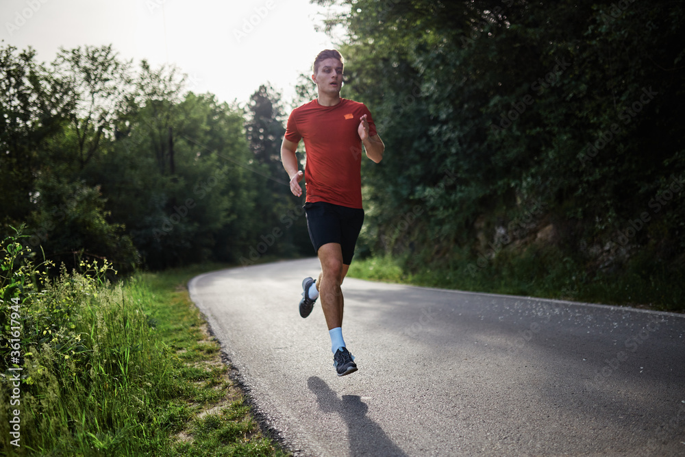 Young man running alone on an empty road Young man running alone on an empty road