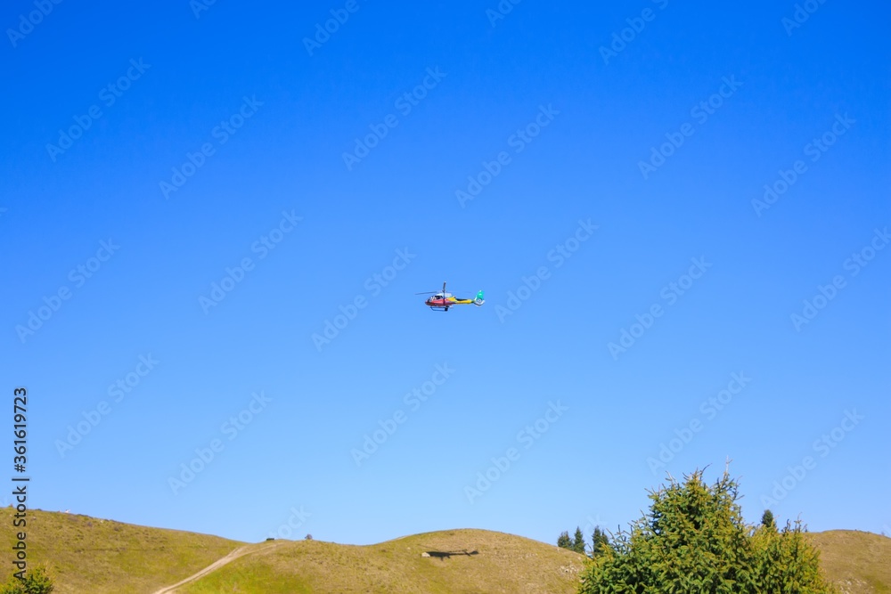 Helicopter Eurocopter EC 130 B4 in blue sky over green hills. Helicopter Eurocopter EC 130 B4 in blue sky over green hills.