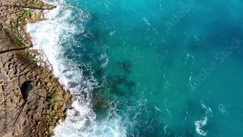 Wonderful turqouise blue ocean water hitting against the rocks - top down view photo