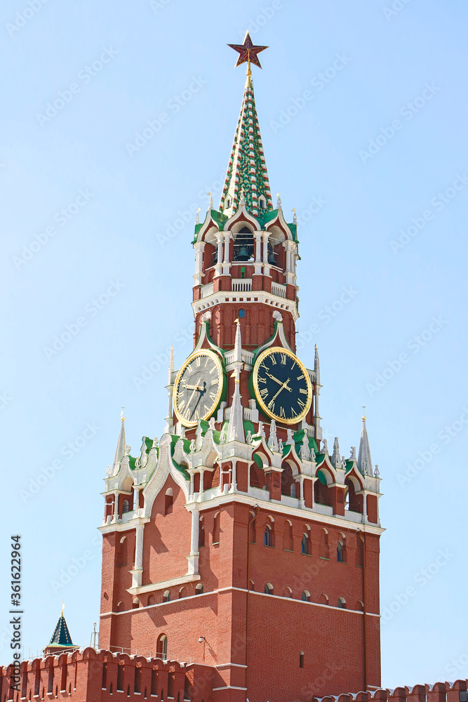 View of Spasskaya Tower with large clock of Moscow Kremlin built from red bricks on a summer morning. Clear blue sky in the background. Theme of travel in Russia. View of Spasskaya Tower with large clock of Moscow Kremlin built from red bricks on a summer morning. Clear blue sky in the background. Theme of travel in Russia.