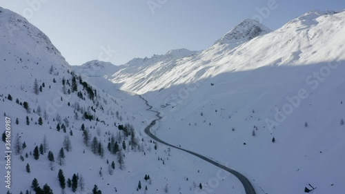 Ariel shot over peaceful long road stretch through the austrian alps mountain range valley photo