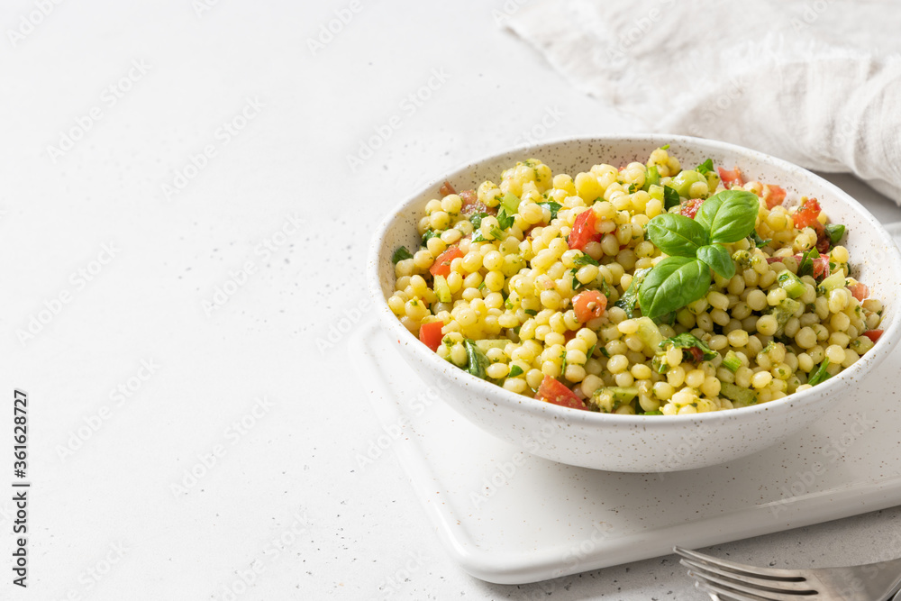 Vegetable salad with pasta ptitim on white table. Close up. Copy space. Vegetable salad with pasta ptitim on white table. Close up. Copy space.