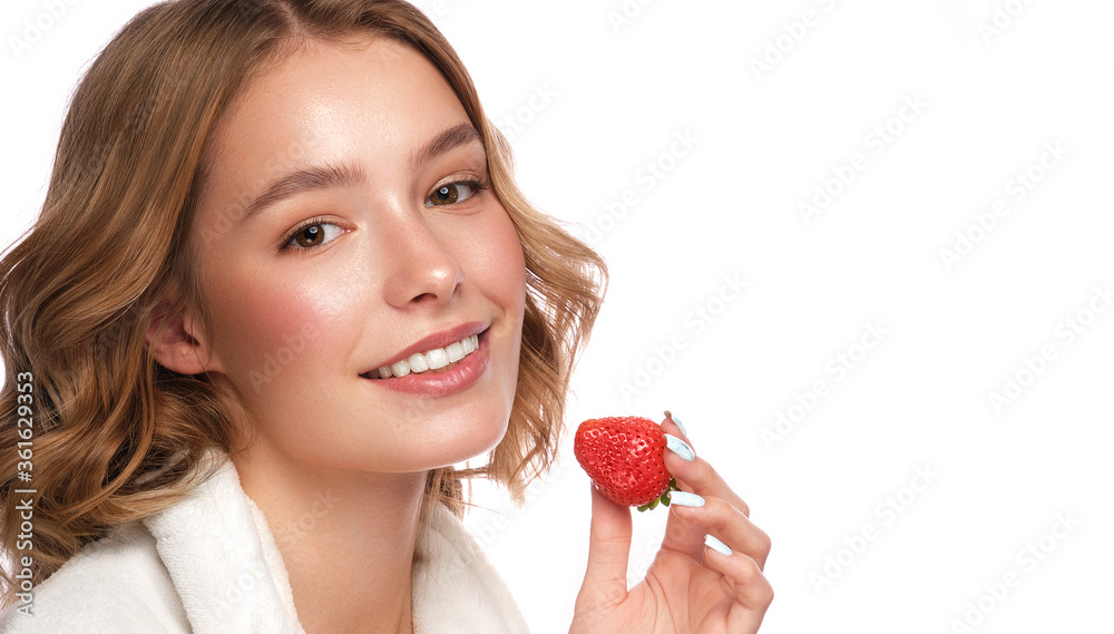Beautiful tender young girl in a white coat with clean fresh skin posing in front of the camera with strawberries in her hands. Beauty face. Skin care. Beautiful tender young girl in a white coat with clean fresh skin posing in front of the camera with strawberries in her hands. Beauty face. Skin care.