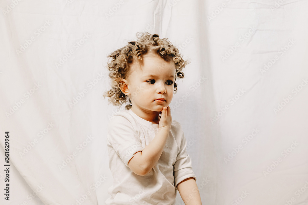 Fototapeta premium Portrait of a little curly girl with freckles dressed in a yellow dress Home family fun parents with baby.
