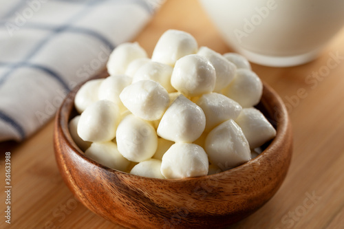 Mozzarella cheese balls in bowl and glass of milk on wooden background