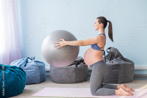 Pregnant caucasian woman on fitness with a ball. Yoga for expectant mothers. Girl in the classroom in preparation for childbirth. Pilates in the last trimester. photo