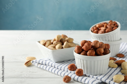 Bowls with different nuts on white wooden background. Vitamin food