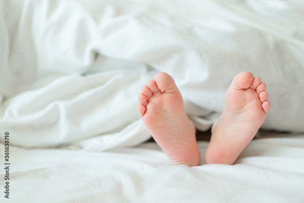 Heels and fingers on the bed. Heels and feet. Children's legs. Barefoot on the bed. Baby legs in bed. Children rest focused on bare feet. Baby bare feet peeking out from under a white blanket. Heels and fingers on the bed. Heels and feet. Children's legs. Barefoot on the bed. Baby legs in bed. Children rest focused on bare feet. Baby bare feet peeking out from under a white blanket.