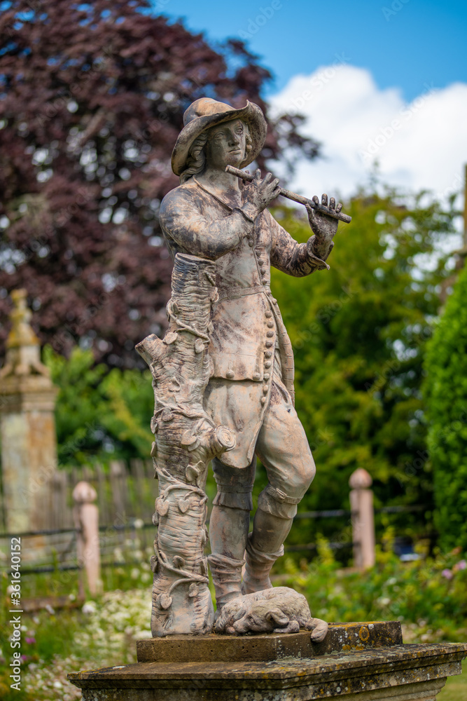 statue of shepherd young boy playing a flute with dog at his feet