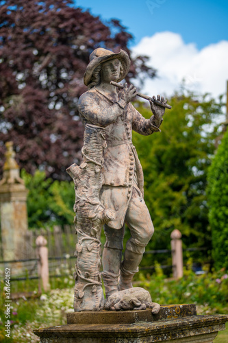 statue of shepherd young boy playing a flute with dog at his feet
