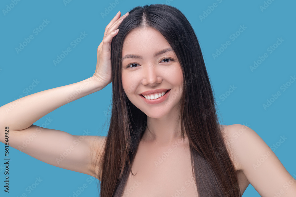 Smiling dark-haired woman touching her beautiful hair Smiling dark-haired woman touching her beautiful hair