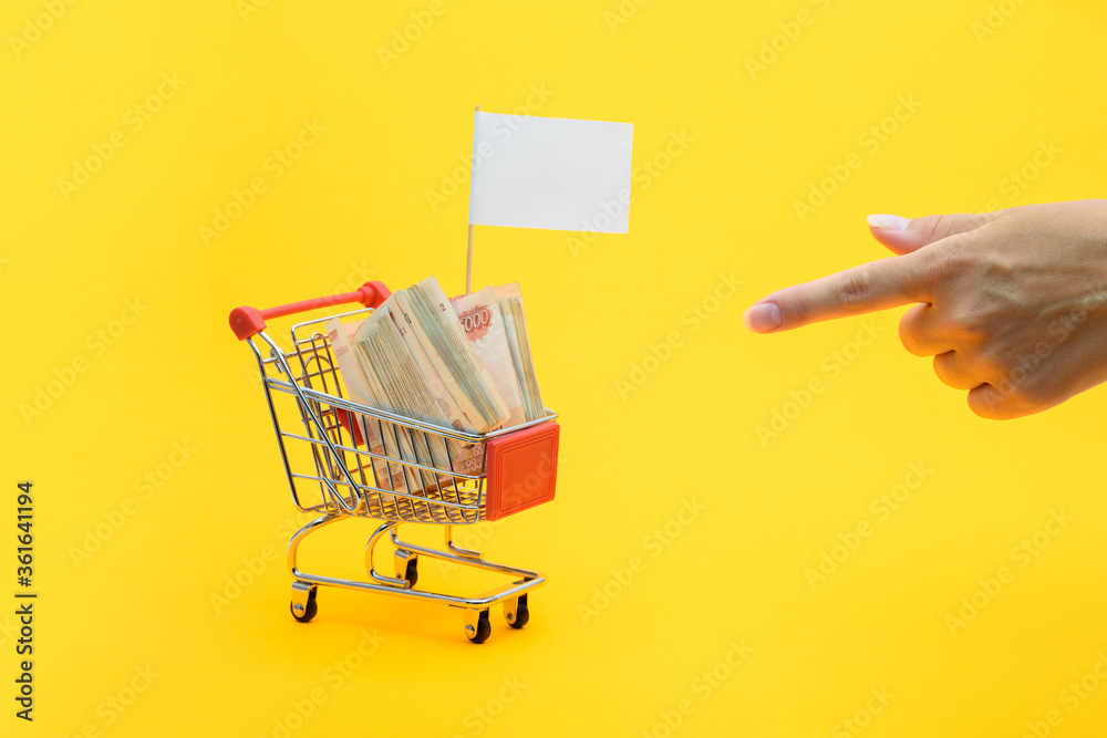 Hand points to a grocery cart with a bundle of notes and a white flag ...