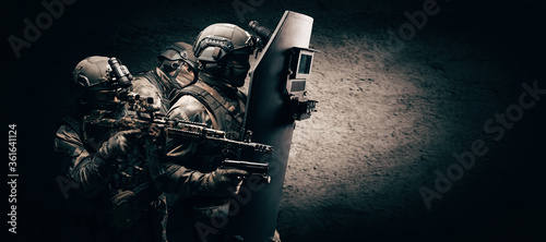Image of three soldiers in a shooting computer game. ESports concept. They hide behind a tactical bulletproof shield. photo