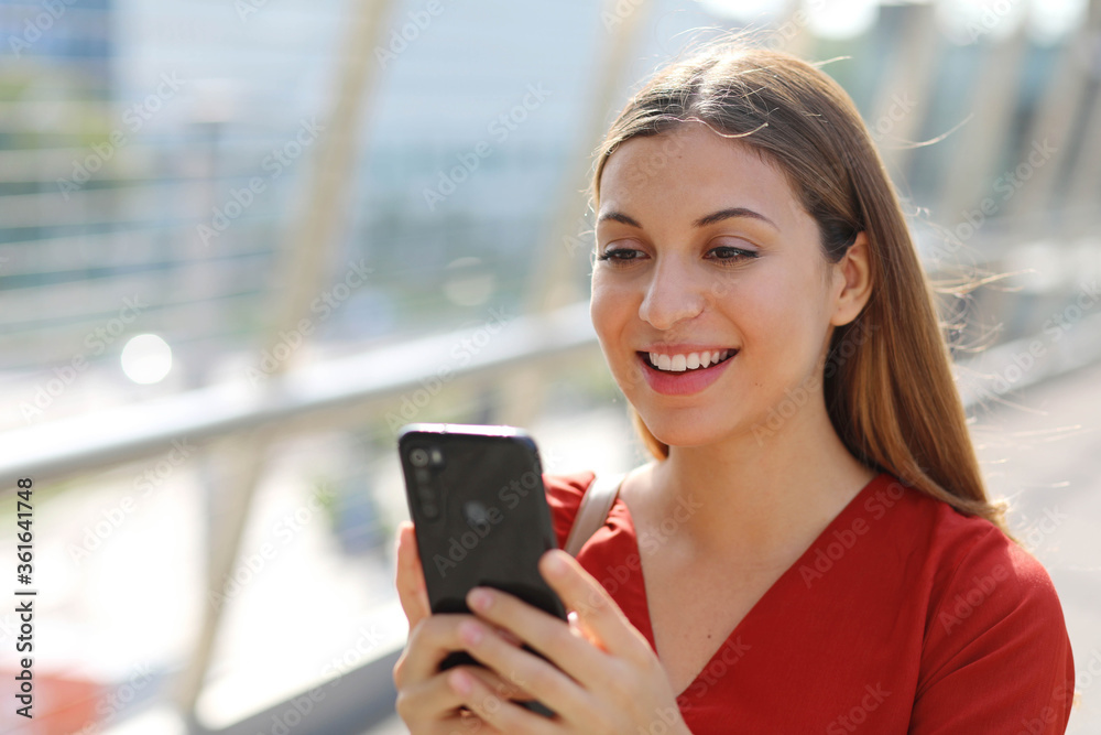 Close up of smiling business woman using shopping online app on smart phone in city street Close up of smiling business woman using shopping online app on smart phone in city street