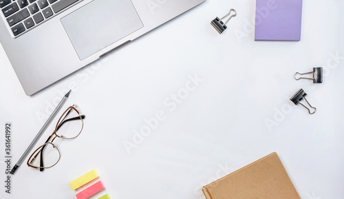 Office workspace on the desktop. Notebook, glasses, stickers, notepad, pencil on a white table.