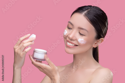 Woman doing skincare procedures using facial cream