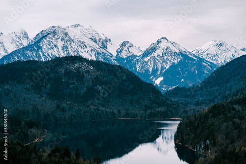 Snow-covered mountains over Alpsee is a lake in Ostallgau district of Bavaria, Germany, located about 4 kilometres southeast of Fussen. It is close to the Neuschwanstein and Hohenschwangau castles.