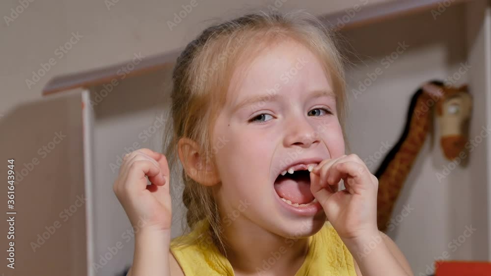 Little girl has her front loose tooth. Milk teeth are ready to drop. The child is happy to grow up Little girl has her front loose tooth. Milk teeth are ready to drop. The child is happy to grow up
