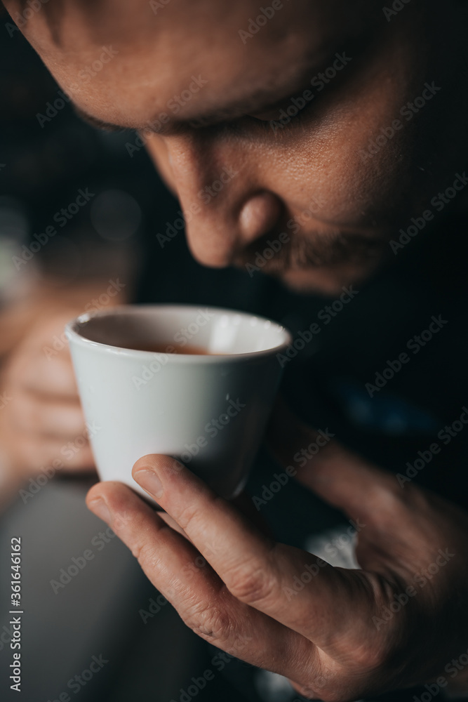 Barista inhales the aroma of fresh espresso from a white cup - a professional assessment of the quality of coffee Barista inhales the aroma of fresh espresso from a white cup - a professional assessment of the quality of coffee