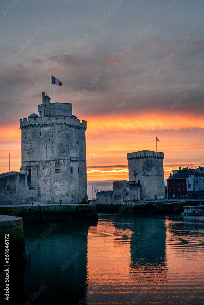 The old harbor of La Rochelle at sunset with its famous old towers. beautiful orange sky. portrait format