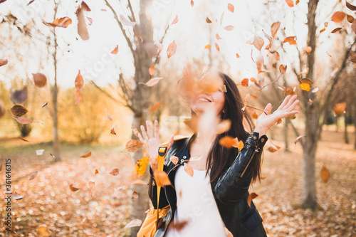 Quadro su tela Cheerful happy girl waving her hands from falling autumn leaves - a gust of wind