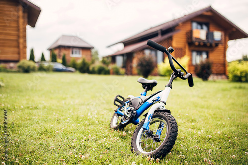 Children bike on a green lawn in the courtyard of a country house - rural property © andrey gonchar