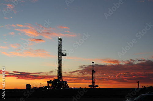 Early sunrise, crack of dawn, showing West Texas landscape with 2 drilling rigs in background