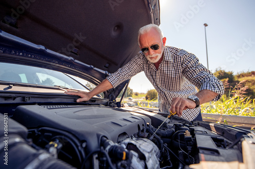Senior man check oil in car.